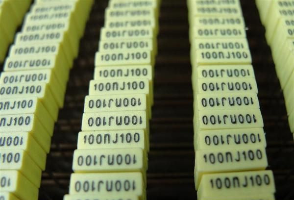 100NJ100 0.1uF 100V Radial Polyester Capacitor - shown as a close-up of multiple yellow rectangular components arranged in vertical rows.
