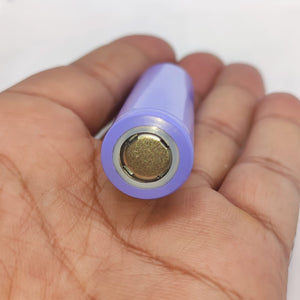 18650 Lithium Ion Cell refurb - a close-up view of the positive terminal end of a cylindrical purple battery held in a person's palm.