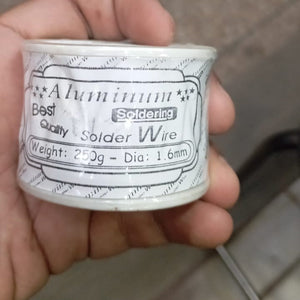 250 Gram 1.6mm Aluminium Best Quality Solder Wire - shown as a close-up of a white plastic spool with a printed label held in a hand.