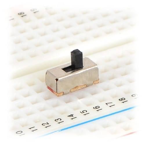 3 Pin 8.5mm Mini Vertical Spdt Slide Switch Toggle Switch - shown as a small silver rectangular component with a black sliding toggle placed on a white breadboard.