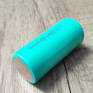 32700 3.2V 4000mAh LiFePO4 Battery - shown as a single, cylindrical, turquoise-coloured battery cell lying on a wooden surface.