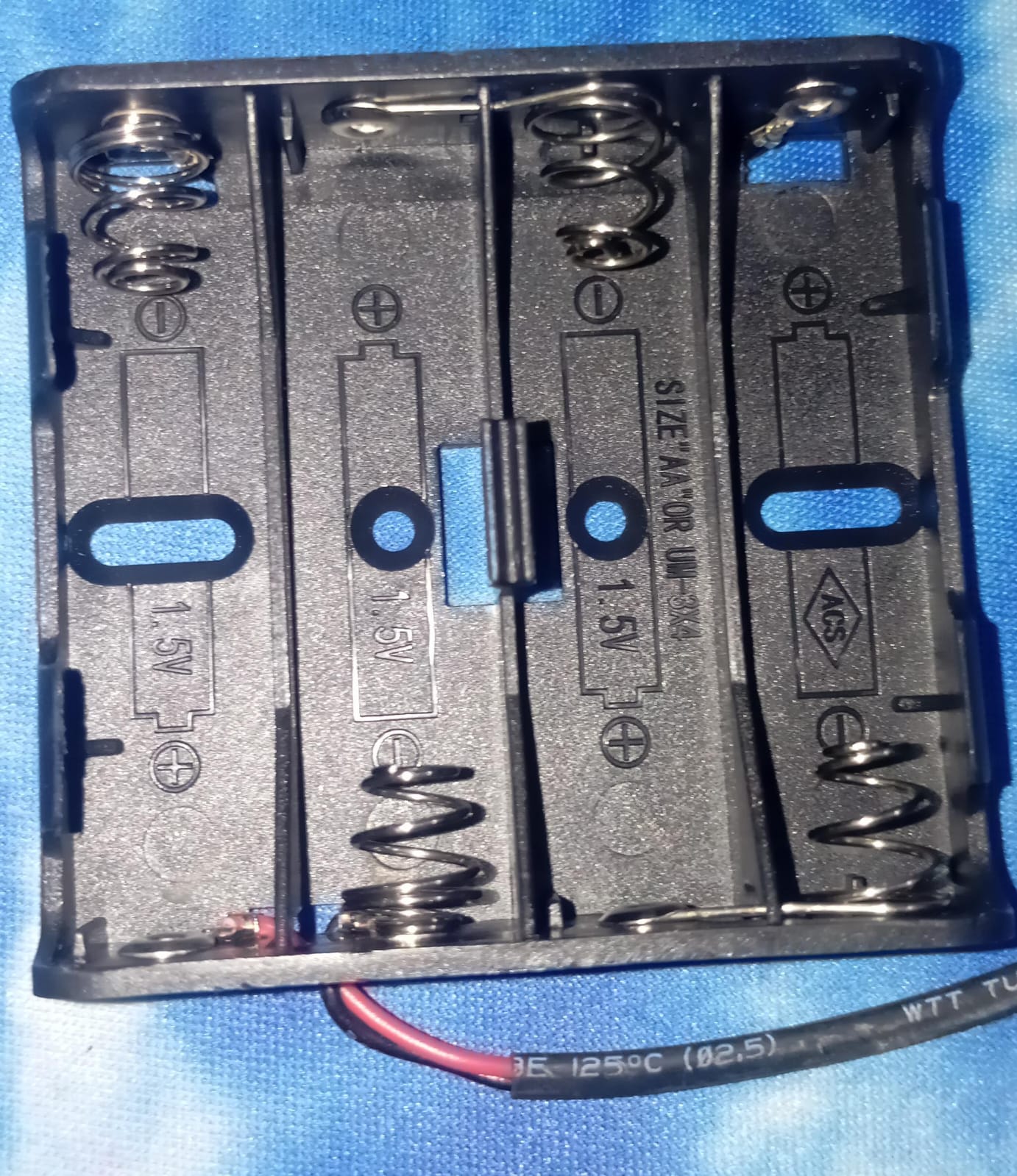 4xaa Battery Holder In Lahore Pakistan - a black plastic four-slot battery case with metal springs and red and black wires attached to the bottom.
