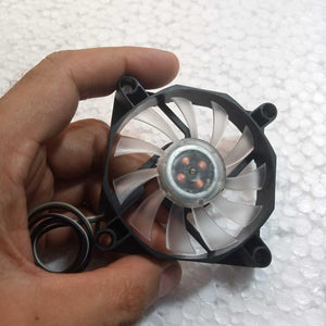 5V Fan With LED - shown as a small black square frame with translucent fan blades and a central hub containing visible copper coils, held by a hand.
