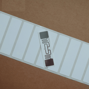 915MHz Uhf Passive RFID Tag Uhf RFID Tag Alien Higgs 3 9662 Epc Global C1G2 Dry Inlay Printable - a single white rectangular adhesive label with a visible copper antenna pattern resting on a roll of similar labels.