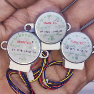 Arduino 5V Stepper Motor 24BYJ - three silver circular motors with white plastic connectors and multi-coloured wiring held in a hand.