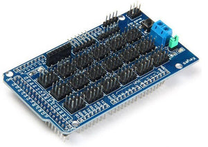 Arduino Mega Sensor Shield - a blue rectangular circuit board featuring numerous black pin headers, a blue screw terminal, and a small push button.