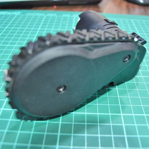 DC Gear Motor With Encoder With Wheel - a black motor assembly with a treaded rubber wheel mounted on a green cutting mat.