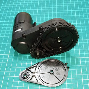 DC Gear Motor With Encoder With Wheel - shown as a black motor assembly with a tracked wheel, a detached side cover, and two small screws on a grid mat.