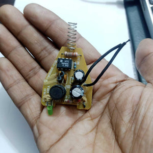 DC To DC Convertor IC 34063A - circuit board held in a palm, featuring a spring antenna, a green LED, two electrolytic capacitors, and black wires.