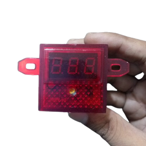 DC Volt Meter 8-30V - held in a hand, featuring a red rectangular housing with a three-digit LED display and a small circular indicator light.