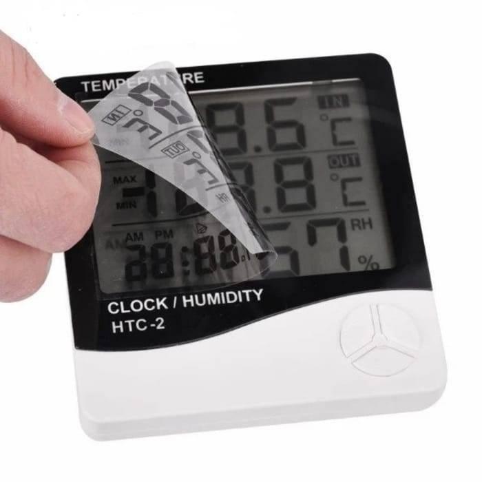Digital Thermometer And Hygrometer Htc-2 - a hand peeling a protective plastic film off the black and white LCD screen displaying digits.