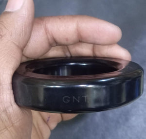 Gnt Ring For Inverter 3 Inch | High-quality Ferrite Core | Digilog.pk - a close-up of a smooth, circular black ferrite core held in a hand with the letters GNT embossed on the side.