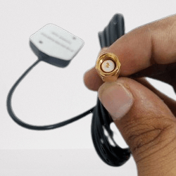 GPS Antenna - External Active Antenna - shown as a close-up of a hand holding the gold-colored SMA connector with the antenna unit and cable attached.