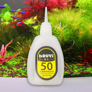 Gr 50G Fast-drying Glue Strong Adhesive Safe Non-toxic Glue Aquarium Landscape Supplies - a white plastic squeeze bottle with a pointed nozzle and a yellow label reading "houyi 50" against an aquarium background.