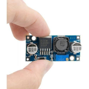 Hw-432 XL6009 DC To DC Boost Converter Voltage Booster - a blue rectangular circuit board with a chip, a coil, two capacitors, and a blue potentiometer held by fingers.