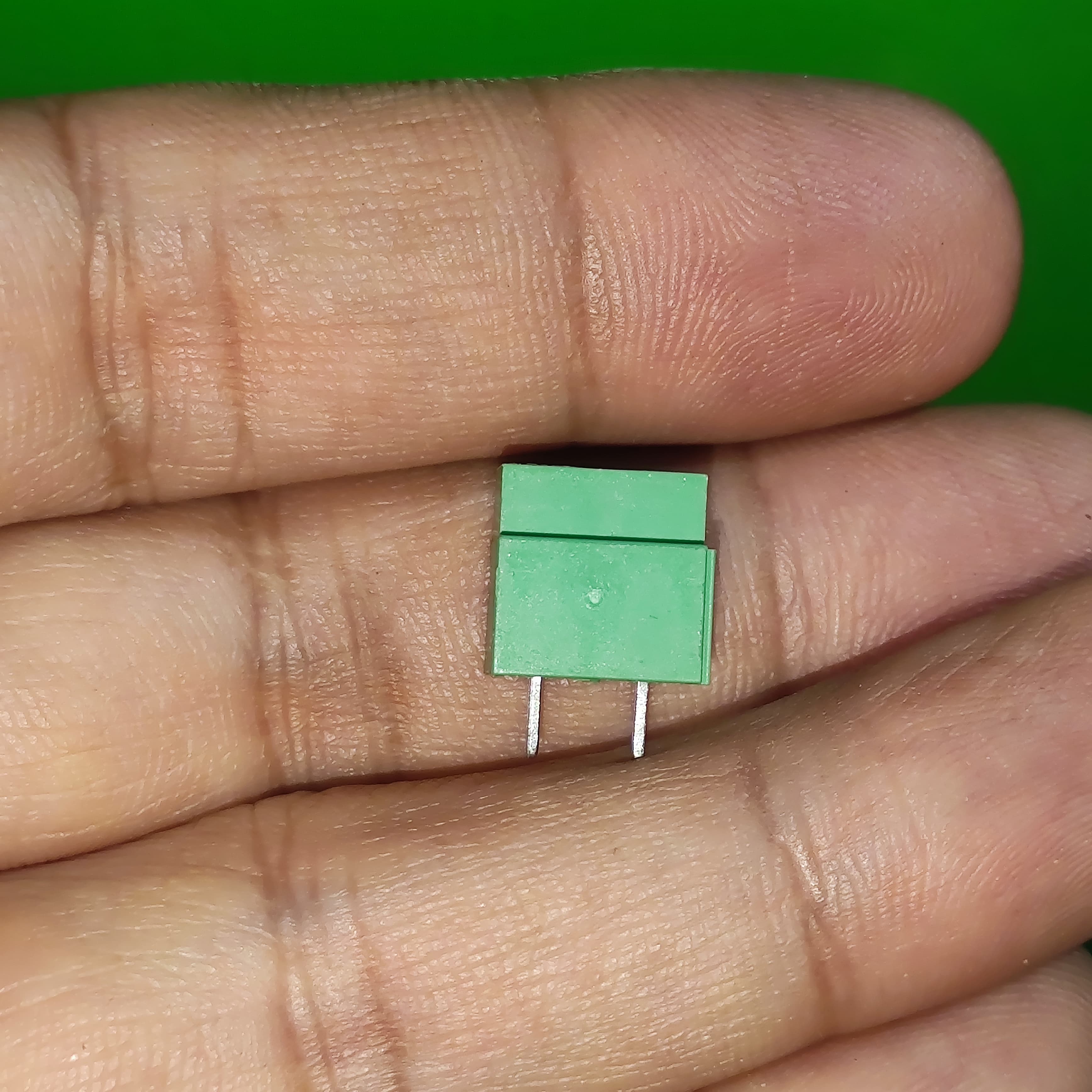 Kf 350 /kf 126 250V 10A 5mm Pitch Green Color 2 Pin Screw Terminal Connector Tblock - shown as a close-up of the green plastic block with two metal pins held between fingers.