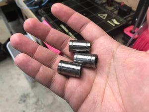 Lm8uu 8mm 8x15x24mm Ball Bearing Bush Bushing For CNC And 3d Printer Pparts - shown as a close-up of three small, cylindrical, metallic silver bearings held in a person's hand.