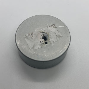 Magnet for storing screws and metal - a circular grey magnetic base with a central hole and a partially torn white label on the top surface.