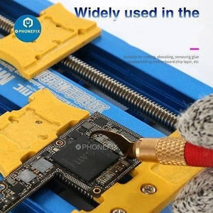 Mechanic 004 Glue Remover Cutting Blades Set For Phone PCB IC Chip - a hand using a gold-handled blade to remove glue from an A11 chip on a PCB held in a blue vice.