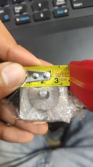 NEMA 11 stepper motor without connector - a close-up view showing the silver square-shaped motor body wrapped in plastic, being measured by a yellow tape measure.
