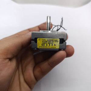 NEMA 14 Stepper motor KH39EM2-045C 0.6A JAPAN SERVO Pancake Stepper Motor - held in a hand, showing the silver metal body, the top shaft, and the yellow specification label.