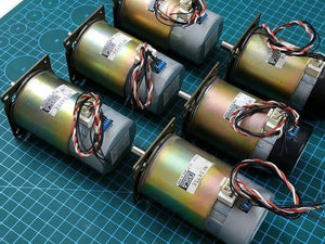 Nisca Servo DC Motor With Encoder NF5475E DC 24V To 38V And 3500 To 5000RPM - a collection of five cylindrical metallic motors with attached wiring harnesses and white connectors on a green cutting mat.