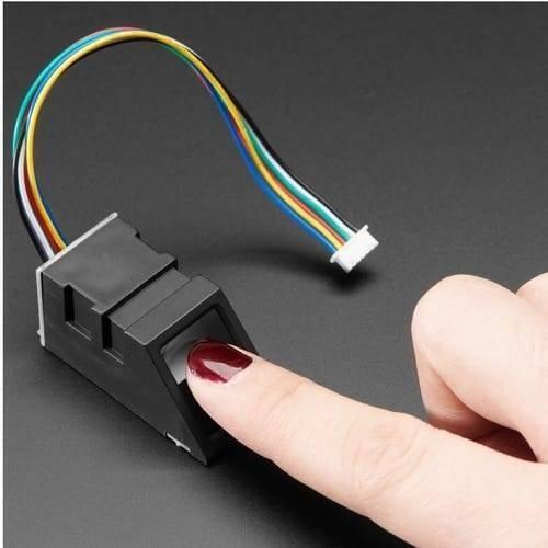 Original Finger Print Sensor R307 Optical Finger Print Scanner Reader Module - a black optical scanner module with a multi-coloured ribbon cable, being tested by a finger.