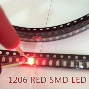 Red SMD 1206 LED Super Bright Light Emitting Diode - a glowing red surface-mount light-emitting diode being tested with probes while housed in a strip of black plastic carrier tape.