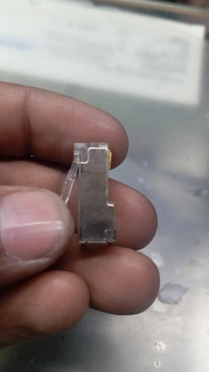RJ45 Connector with meteal casing - with metal casing, a close-up view of the silver-toned rectangular connector held between fingers, showing its transparent plastic top.
