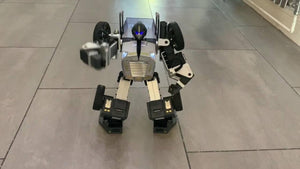 Robosen T9 - Advanced Programmable And Convertible Robot - STEM: Fun, Educational With Voice And App Control - standing in a humanoid form on a tiled floor with its right arm extended.