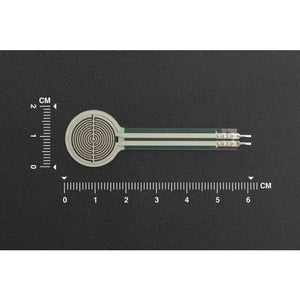 RP-C18.3-LT Thin Film Pressure Sensor - a circular white sensor with a flat ribbon tail and two metal connectors, shown against a centimeter ruler scale.