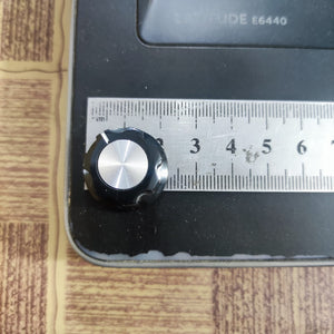 Screw Type Tightening Knob For Potentiometer - a black and silver knob shown next to a metal ruler for scale.