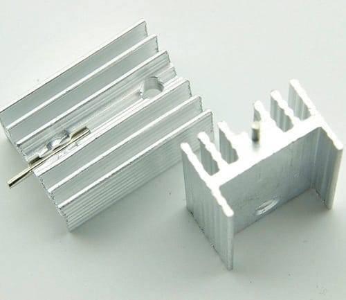 Silver Aluminium To 220 Heat Sink - two silver-coloured, finned metal heat sinks with mounting holes, one with a metal pin inserted.