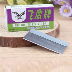 Single Edge Safety Razor Blade For Mobile Phone Repairing Opening Frame Cutting Polarizer Film Remover Tool - a metal blade placed in front of its purple and green cardboard packaging box on a wooden surface.