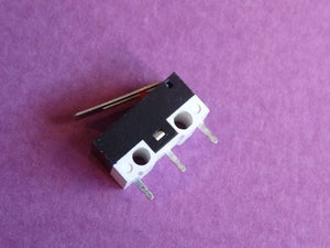 Small Microswitch / Limit Switch - shown in a close-up angle, featuring a black and white rectangular body with a metal lever and three metal terminal pins.