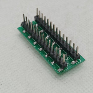 SMD DSPIC30F2010 - adapter board featuring a green rectangular PCB with two parallel rows of vertical male pin headers soldered onto the surface.