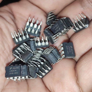 Stock Lot LM2574 Adj Voltage Buck Regulator IC - a pile of black, rectangular, 8-pin integrated circuit chips held in a human hand.