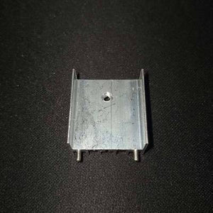 TO3P Black And Silver Heat Sink - a silver-colored aluminum heat sink with a central mounting hole and two pins on a black textured background.