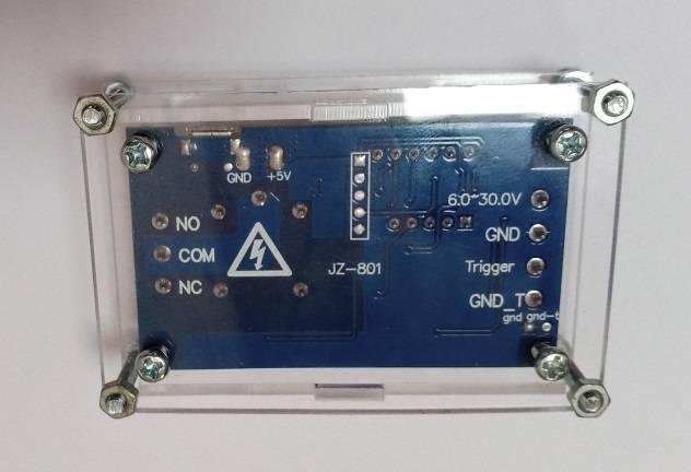 Transparent Acrylic Case For Timer Relay Module - the blue circuit board inside with labeled ports for NO, COM, NC, 6.0-30.0V, GND, and Trigger.