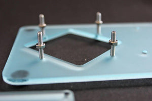 Unassembled 4dof Robotic Arm - a close-up of a light blue acrylic plate with four metal threaded studs and nuts installed.