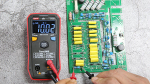 UNI-T UT123D Smart Digital Multimeter – Auto-Identify, EBTN Display, AC/DC Voltage, Capacitance, Resistance, NCV, Diode & Continuity, One-Button Operation - with a black and red casing, showing a 10.02 MΩ reading on its EBTN display while testing a green circuit board.