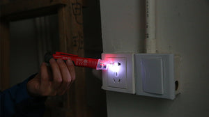 UNI-T UT12D Non-Contact AC Voltage Detector Pen – 24V to 1000V NCV Tester with LED Flashlight, Buzzer & LED Alert, Dual High/Low Sensitivity, Auto Power-Off, 1m Drop-Proof - a red handheld tester with a glowing red LED tip, being used to check a wall power outlet.