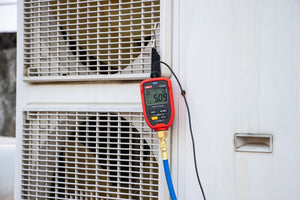 UNI-T UT336P KIT Wireless Digital Pressure Gauge with Temperature Clamp – -1 to 60 bar, HVAC Refrigerant Manifold, 94 Refrigerants, App Connected - hanging from an AC unit with a blue hose connected, showing 5.09 on its digital display.