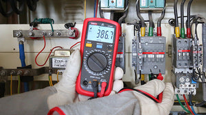 UNI-T UT39A+ Digital Multimeter – 4000 Count, AC/DC 1000V, 10A, Capacitance, hFE, NCV, Diode & Continuity, CAT II 1000V / CAT III 600V - held by gloved hands, displaying 386.7V AC while connected to electrical control panel terminals with red and black probes.