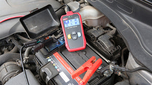 UNI-T UT673A Automotive Battery Tester – 12V/24V, CCA 40–2000, Cranking & Charging System Test, Internal Resistance, Battery Health Analyzer - a red handheld device with a screen showing menu icons, connected to a car battery with black and red clamps.