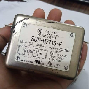 Used Noise Filter EMI Filter Anti-Interference Noise Signal Filtration Single Phase Mains Filter 125V 250V - Okaya SUP-B7715-F noise filter, a silver rectangular metal EMI filter held in a hand, showing the label with specifications and wiring diagram.