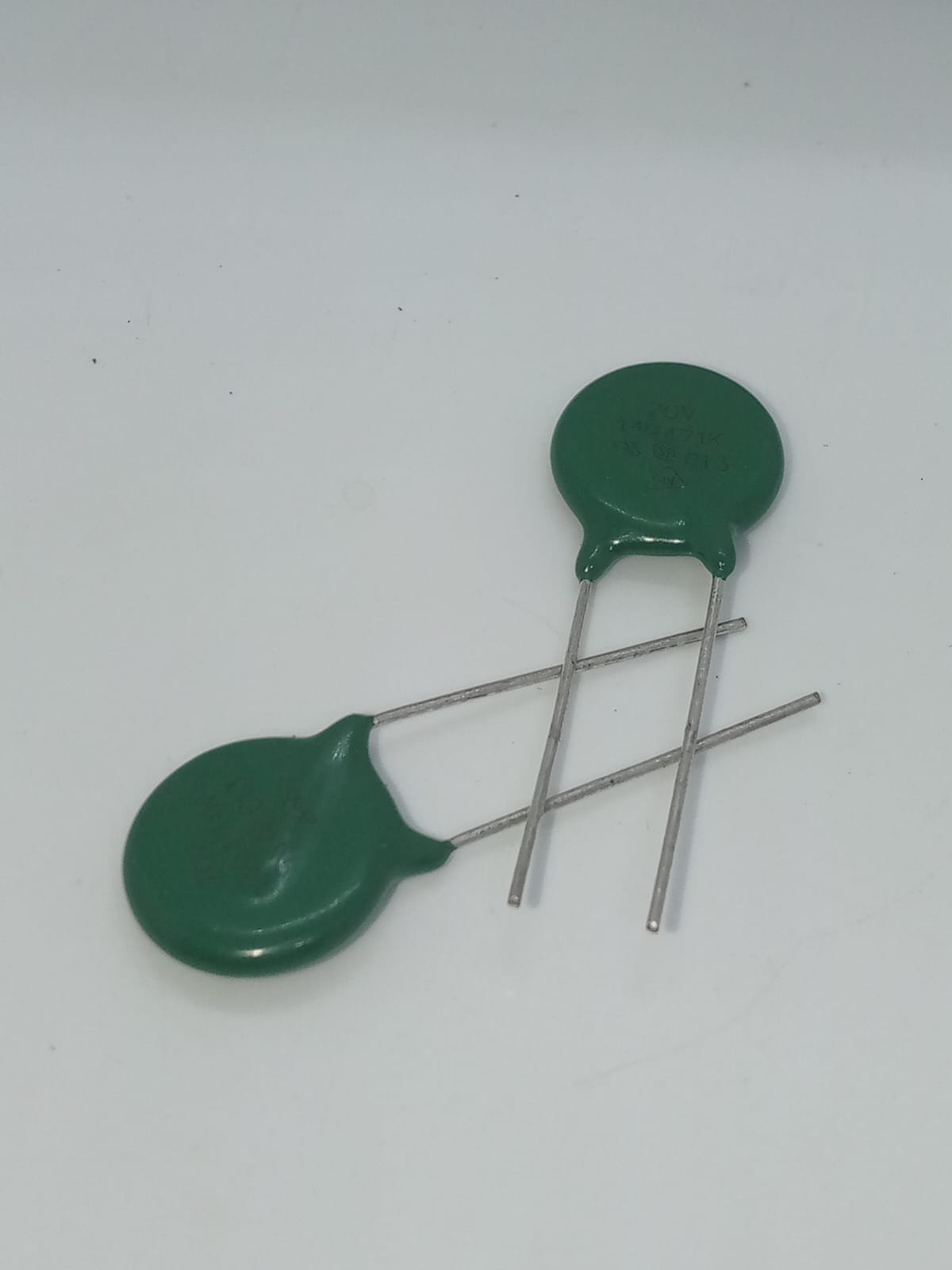 Varistor 14D471K - two green disc-shaped electronic components with two metal leads each, positioned on a white background.