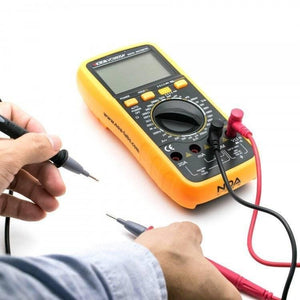 VC9805A+ Digital Multimeter - shown with a blank screen, a central dial, buttons, and red and black test leads held by a person's hands.