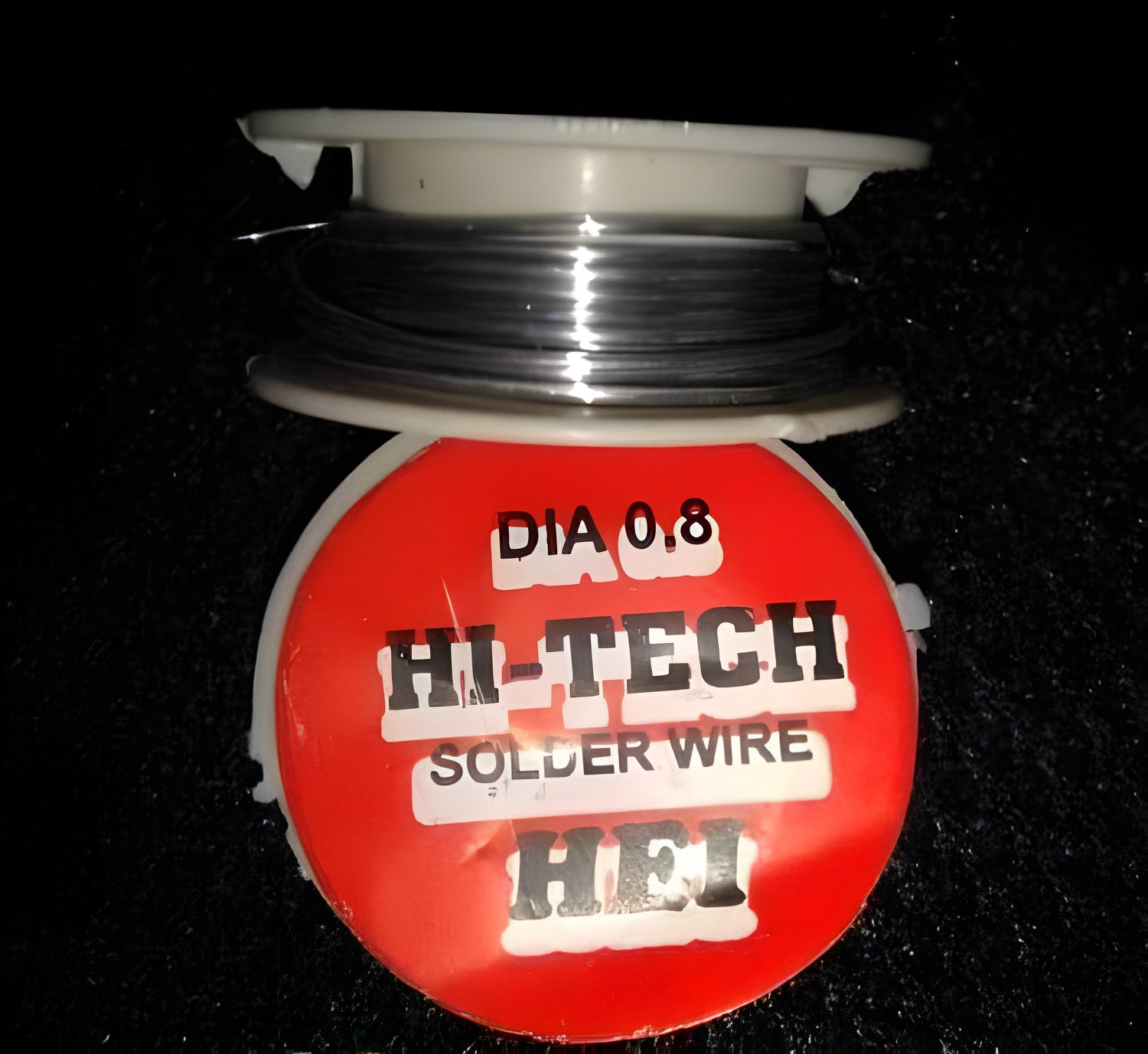 0.8mm 2.5ft Soldering Wire - shown as a spool of thin metallic wire wrapped around a white plastic reel with a red circular label reading HI-TECH.