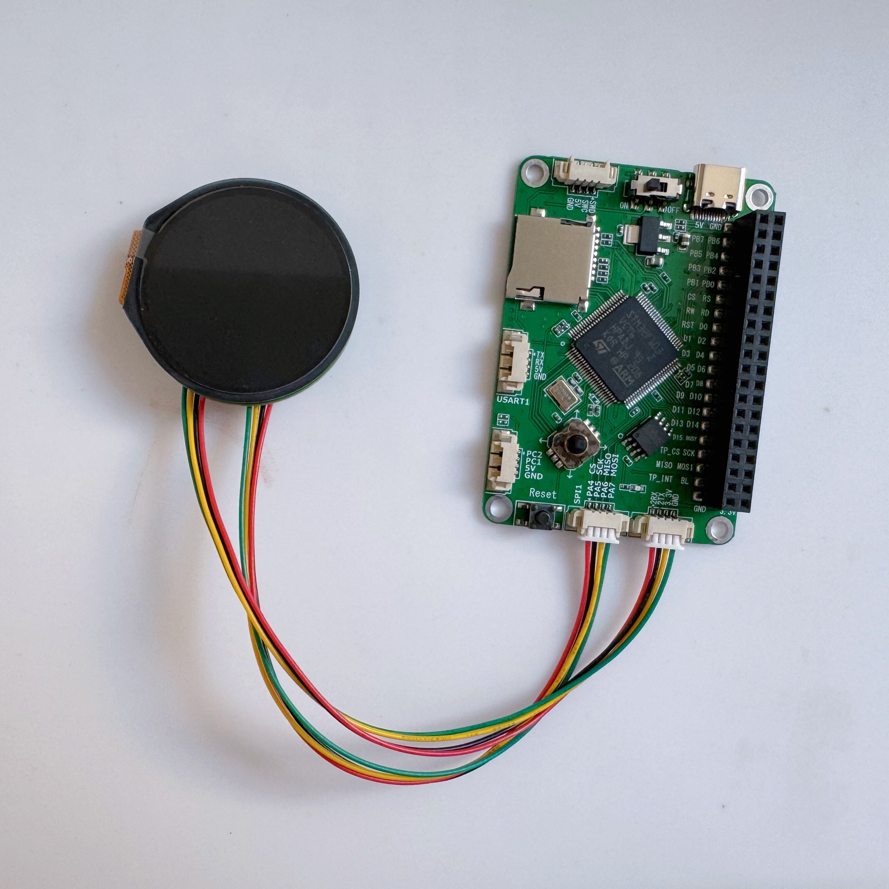 1.28 Inch IPS Round LCD Display Module With Capacitive Touch 2 Dupont Cables — ESP32 - — ESP32 shows a round black display connected to a green circuit board.